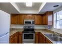 Bright kitchen with stainless steel appliances and wooden cabinets with stylish countertops at 3330 W Danbury Dr # E203, Phoenix, AZ 85053