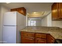 Kitchen with granite counters, wood cabinets, and white refrigerator at 3330 W Danbury Dr # E203, Phoenix, AZ 85053