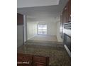View of a spacious living room with plush carpet and a sliding glass door to a balcony, seen from the kitchen at 3330 W Danbury Dr # E203, Phoenix, AZ 85053