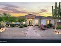 Elegant home exterior featuring desert landscaping, a stone accent, and a covered entry, illuminated by landscape lighting at 3946 N Pinnacle Hills Cir, Mesa, AZ 85207