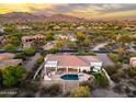Aerial view showcases home's backyard with pool, spa, and desert landscaping amidst a scenic neighborhood and golf course at 3946 N Pinnacle Hills Cir, Mesa, AZ 85207