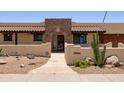 Inviting home featuring a stone arch entrance, desert landscaping, and a warm, earthy color palette at 1551 E Glencove St, Mesa, AZ 85203