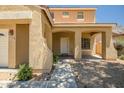 Charming covered front entrance with decorative columns, desert landscaping, and a well-lit walkway at 17766 W Caribbean Ln, Surprise, AZ 85388