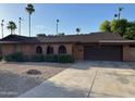 A single-story home featuring brick accents, a two-car garage, and desert landscaping at 3740 E Mercer Ln, Phoenix, AZ 85028