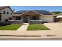 Inviting single-story home featuring a well-manicured lawn and modern solar panels on the roof at 6352 W Campo Bello Dr, Glendale, AZ 85308