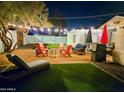 This backyard retreat has string lights, comfortable seating, artificial grass, and a modern fire pit at 1801 N 87Th Pl, Scottsdale, AZ 85257