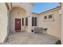 Inviting entryway with a covered porch, a bench, and a beautiful red front door at 18203 W Port Royale Ln, Surprise, AZ 85388