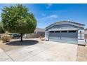 Single-story home featuring a well-maintained lawn and attached two-car garage with grey paint at 310 E Payton St, San Tan Valley, AZ 85140