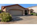 View of the home's front exterior and driveway, showcasing the attached garage and desert landscape at 5314 W Bowker St, Laveen, AZ 85339