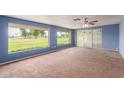 Bright living room with large windows, ceiling fan, and neutral carpet at 10621 W Oakmont Dr, Sun City, AZ 85351