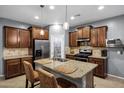 A modern kitchen with wood cabinets, stainless steel appliances and a granite countertop island with seating at 20194 N Riverbank Rd, Maricopa, AZ 85138