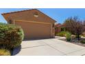 Single-story home with a two-car garage and desert landscaping featuring beautiful rocks and thriving plants at 21893 N 261St N Ave, Buckeye, AZ 85396