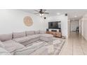 Comfortable living room with a large sectional sofa, ceiling fan, and access to the hallway at 37287 N Azteca Rd, San Tan Valley, AZ 85140