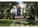 Charming home entrance featuring lush landscaping, a brick walkway, and an impressive arched doorway at 5610 E Sanna St, Paradise Valley, AZ 85253