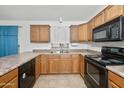 Well-lit kitchen features wooden cabinets, dual basin sink, and black appliances at 742 E Lovegrass Dr, San Tan Valley, AZ 85143