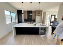 A modern kitchen with a large island, stainless steel appliances, and sleek black and wood cabinetry at 9027 S 19Th St, Phoenix, AZ 85042