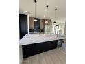 A modern kitchen with a large island, stainless steel appliances, and sleek black and wood cabinetry at 9027 S 19Th St, Phoenix, AZ 85042
