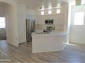Bright, all-white kitchen featuring stainless steel appliances, laminate flooring, and lots of natural light at 9233 E Neville Ave # 1011, Mesa, AZ 85209