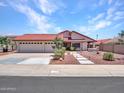 A beautiful single-story house featuring a three car garage, red tile roof, and desert landscape at 12641 S 39Th Pl, Phoenix, AZ 85044