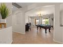Spacious game room with an elegant chandelier, a pool table, and an open archway to the rest of the home at 1321 E Monteleone St, San Tan Valley, AZ 85140