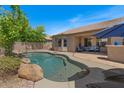 Backyard pool area featuring a free-form pool, a covered patio with an outdoor seating area, and mature landscaping at 1321 E Monteleone St, San Tan Valley, AZ 85140