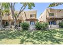 Charming townhome with well-manicured lawn, mature trees, and welcoming sign with light blue door and window trim at 1446 E Grovers Ave # 13, Phoenix, AZ 85022