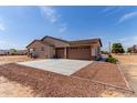 Exterior view of a beige stucco home featuring a three-car garage and a spacious concrete driveway at 20310 W Hubbard Rd, Buckeye, AZ 85326