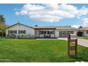 Beautiful single-story home showcasing a lush green lawn, cozy front porch seating, and modern garage door at 615 E Winter Dr, Phoenix, AZ 85020