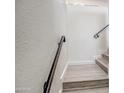 Close-up of a bright staircase featuring wood-look steps and a sleek black handrail, offering a modern design at 7300 N Dreamy Draw Dr # 202, Phoenix, AZ 85020