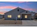 Charming home showcasing warm interior lighting and beautiful sunset hues in the sky above at 9471 W Magnum Dr, Arizona City, AZ 85123