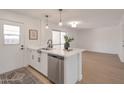 Stylish kitchen island with stainless steel dishwasher, white cabinets and countertops, and modern fixtures at 1051 E Millett Ave, Mesa, AZ 85204
