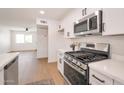 Well-equipped kitchen featuring stainless steel appliances, white cabinets, and an open layout to the living area at 1051 E Millett Ave, Mesa, AZ 85204
