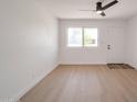 Bright living room featuring wood-look flooring, a modern ceiling fan, and a light-filled window at 1051 E Millett Ave, Mesa, AZ 85204