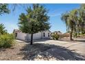 A driveway leads to a home with desert landscaping, shrubs, and trees under a sunny sky at 1225 N 159Th Ln, Goodyear, AZ 85338