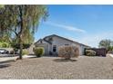 Spacious single-story home featuring desert landscaping with gravel and various trees under a blue sky at 1225 N 159Th Ln, Goodyear, AZ 85338