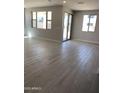 Bright living room with neutral walls, wood-look tile flooring, and sliding glass doors at 4924 W Brown St, Glendale, AZ 85302