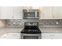 Modern kitchen featuring stainless steel appliances, stylish backsplash, and white cabinetry at 1430 N Ashland --, Mesa, AZ 85203