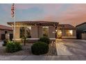 Charming single-story home featuring a tiled roof, landscaped front yard, and an American flag on a pole at 16077 W Anasazi St, Goodyear, AZ 85338