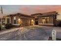 Attractive single-story home with garage, desert landscaping and a long driveway leading to the entrance at 16077 W Anasazi St, Goodyear, AZ 85338