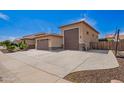 View of the side of the house, showcasing the three-car garage and extended driveway for extra parking space at 18334 W Marshall Ln, Surprise, AZ 85388