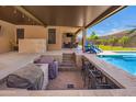 Covered patio features a full outdoor bar, seating, and clear view of the sparkling pool at 18334 W Marshall Ln, Surprise, AZ 85388