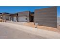 Modern home with a three-car garage, gray tones, clean lines, and fresh desert landscaping at 5145 N Ascent Dr, Scottsdale, AZ 85251