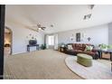 Comfortable living room featuring plush carpeting, neutral paint, and a cozy seating area with a sofa and ottoman at 15537 W Port Royale Ln, Surprise, AZ 85379