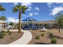 Community playground featuring a shade structure, slides, and climbing elements with palm trees at 1859 S 181St Dr, Goodyear, AZ 85338