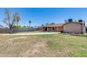 Spacious backyard with a covered patio, mature trees, block fencing and a large grassy area at 1930 W Voltaire Ave, Phoenix, AZ 85029