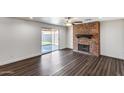 Living room featuring a brick fireplace, hardwood floors, and a sliding glass door to the backyard at 1930 W Voltaire Ave, Phoenix, AZ 85029