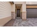 Covered front entry featuring stone accents, neutral stucco, and a modern garage door at 21411 W Meadowbrook Ave, Buckeye, AZ 85396