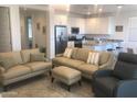 Open-concept living room with couches and modern kitchen, ideal for entertaining at 25109 N 173Rd Dr, Surprise, AZ 85387