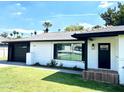 This home has white brick and a black trim, showcasing a well-manicured lawn and detailed landscaping at 541 W Marlette Ave, Phoenix, AZ 85013