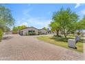 Long paver driveway leads to an elegant home with well-maintained landscaping and mature trees at 8213 E Sharon Dr, Scottsdale, AZ 85260